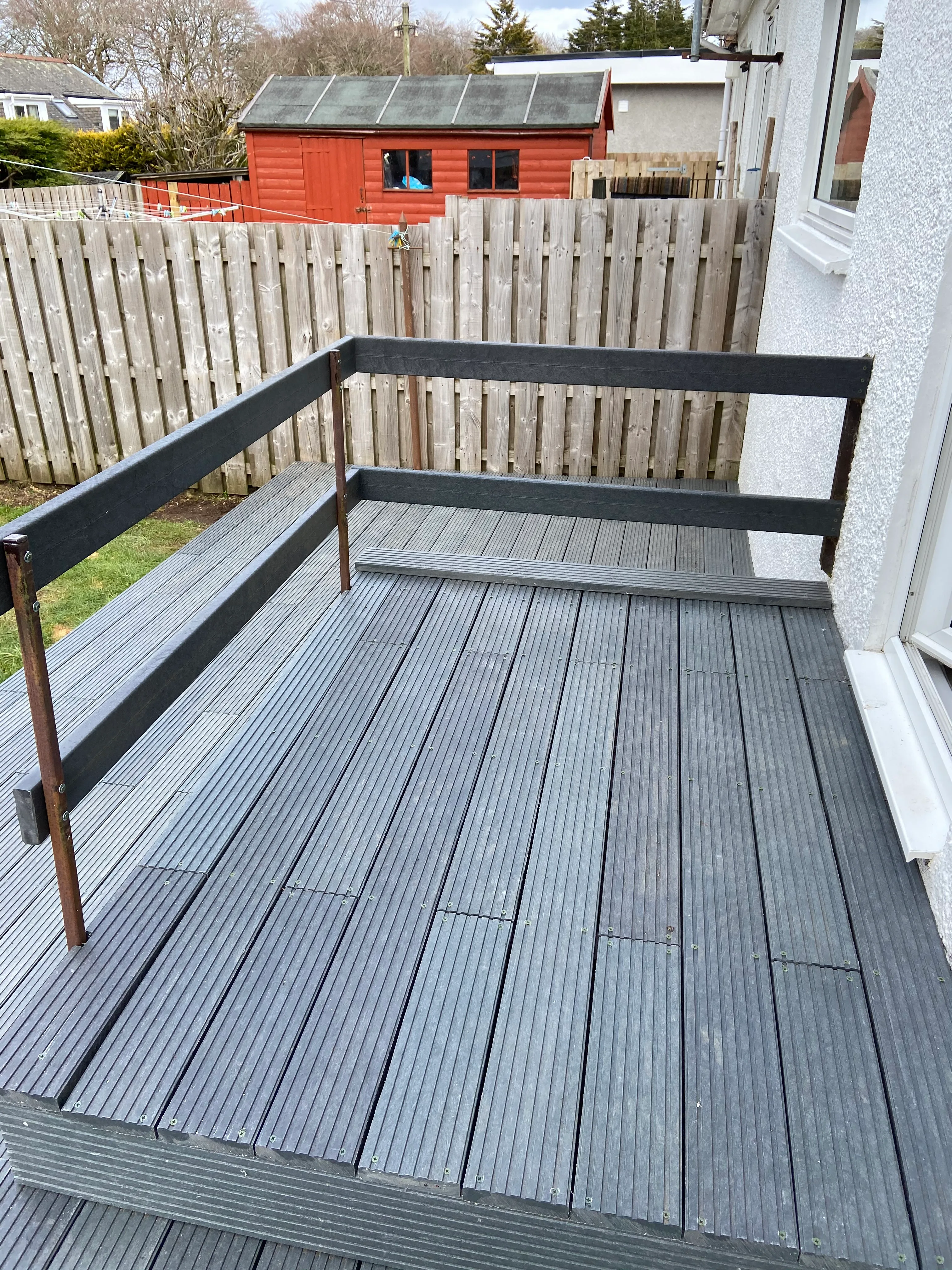 Installed grey recycled plastic decking with black subframe posts visible