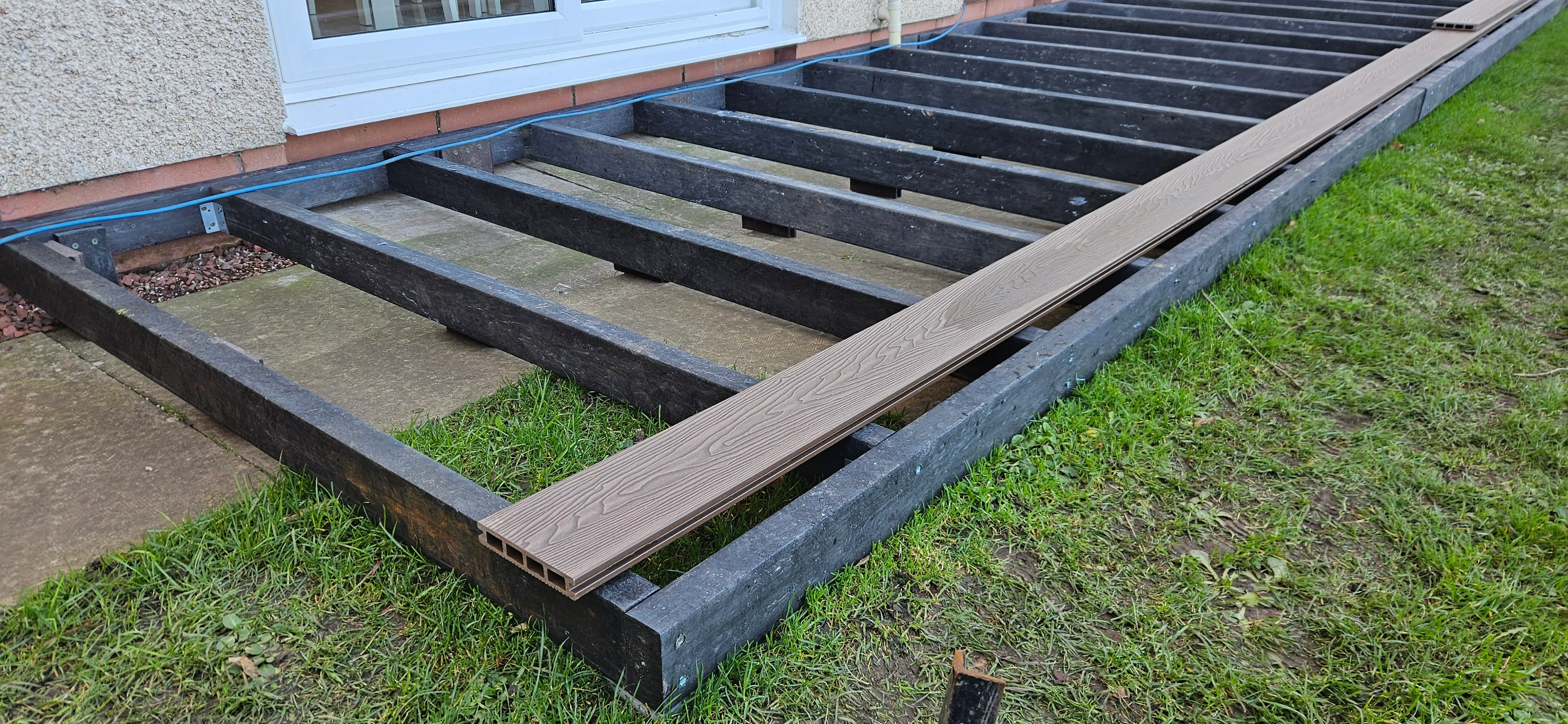 Recycled plastic decking subframe with first board being installed