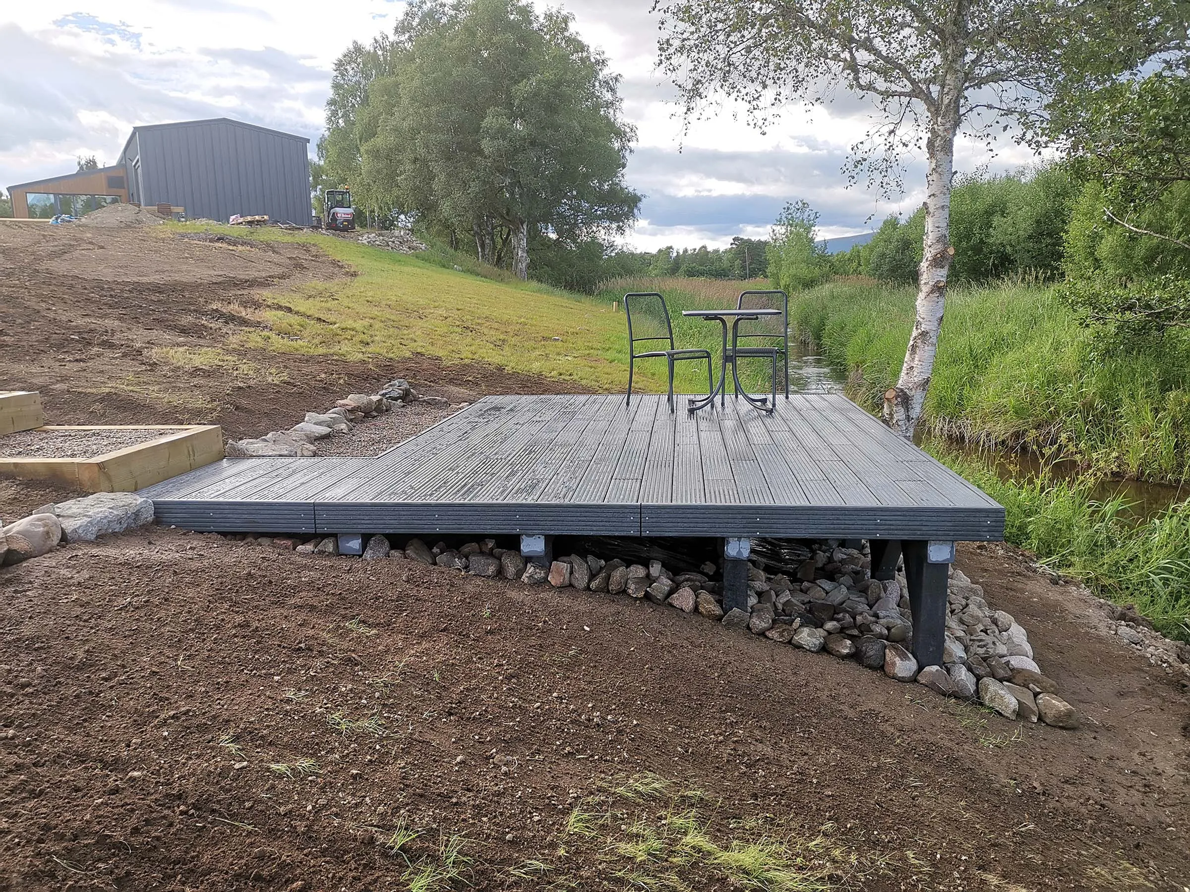 Completed recycled plastic deck installation with grey boards and stone gabion surround